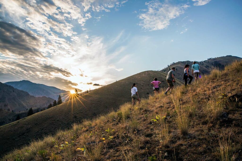 Group of people hiking on a scenic mountain trail during golden hour